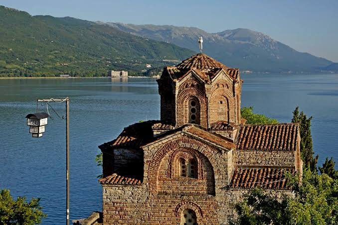 A medieval stone church above a lake